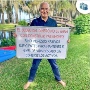 Carlos Devis en un parque sostiene un tablero con texto sobre el juego del dinero. En blog de lo mejor de octubre
